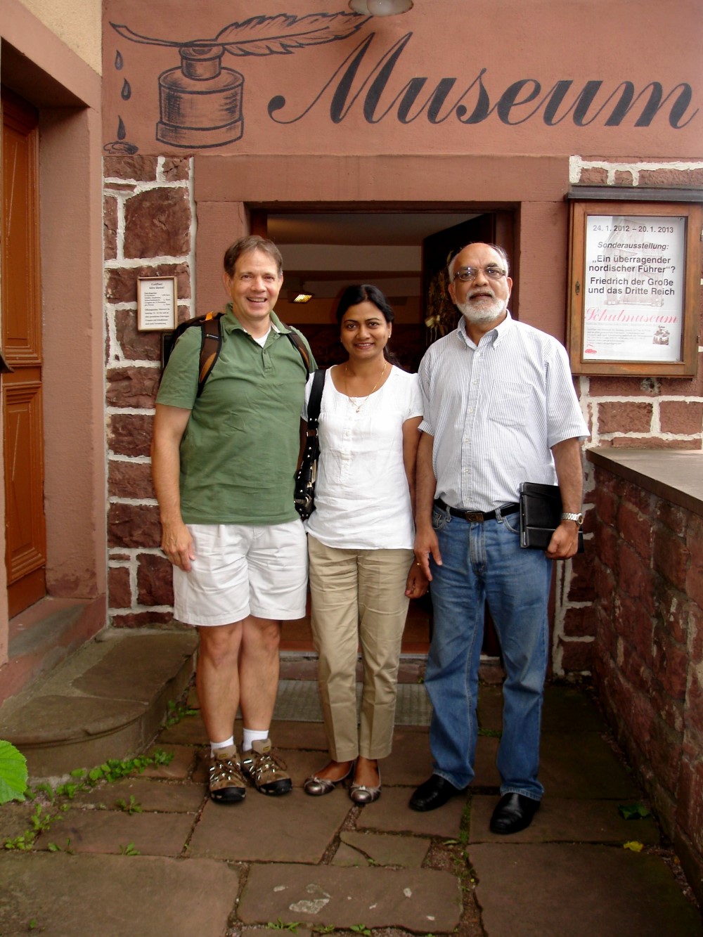 von links vor dem Lohrer Schulmuseum: Gordon Babst, heute Professor fr Politische Philosophie an der CHAPMAN-UNIVERSITT in Orange, Alka Singh und ihr Ehemann Ramesh Singh, ebenfalls Professor an der CHAPMAN-UNIVERSITT in Orange, zur Zeit beim Max Planck Institut/Mainz, beim zweiten Besuch des Museums von Herrn Babst am 11 Juli 2012. Frau und Herr Singh waren sehr beeindruckt vom Schulmuseum und erklrten, sie htten noch nie ein derartiges Museum gesehen, aber gleich verstanden, worum es ginge.