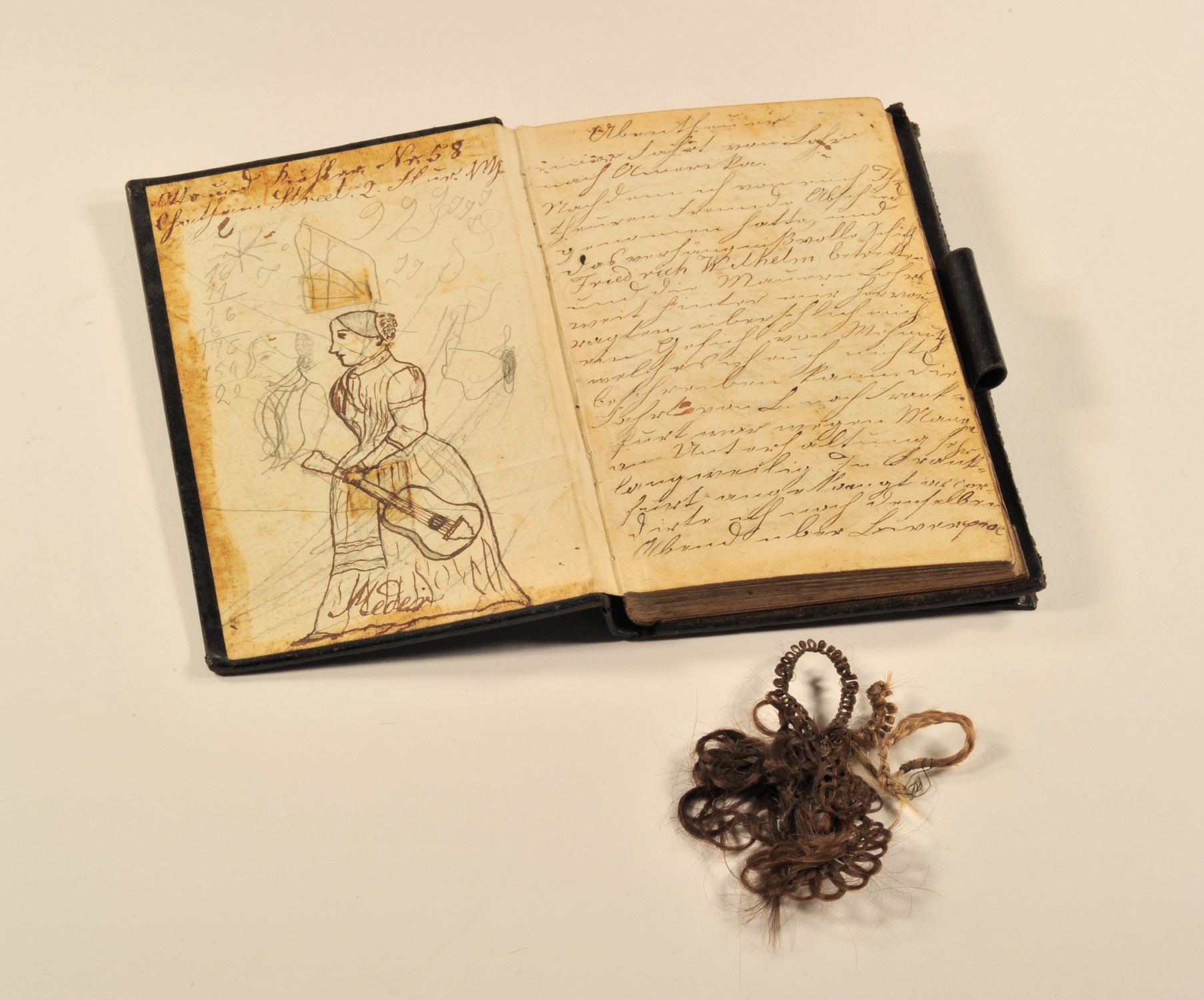 Das geffnete Tagebuch des Franz Niedermaier und  kunstvoll geflochtene kleine Haarteile in der Umschlagtasche des Tagebuches.